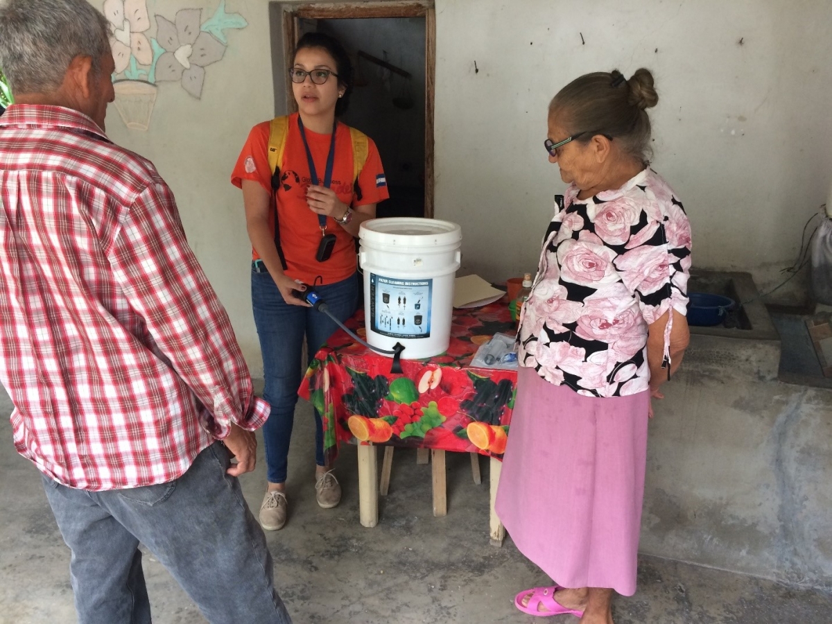 Mittchel Benitez of Global Brigades shows Don Bruno and Doña Adela how to use the water filter.