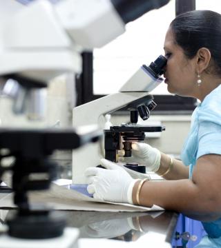 Indian woman looking through a microscope