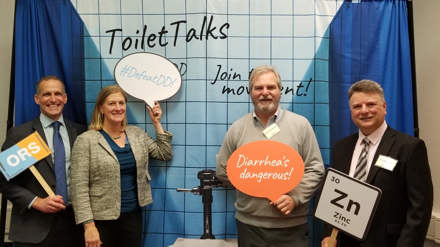 Group posing in front of a toilet stall photo backdrop