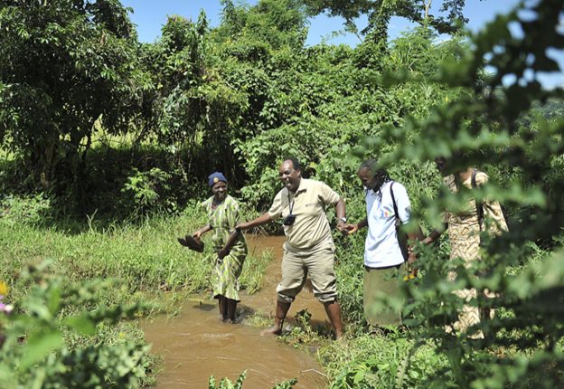 Alfred Ochola leads a group across a river.