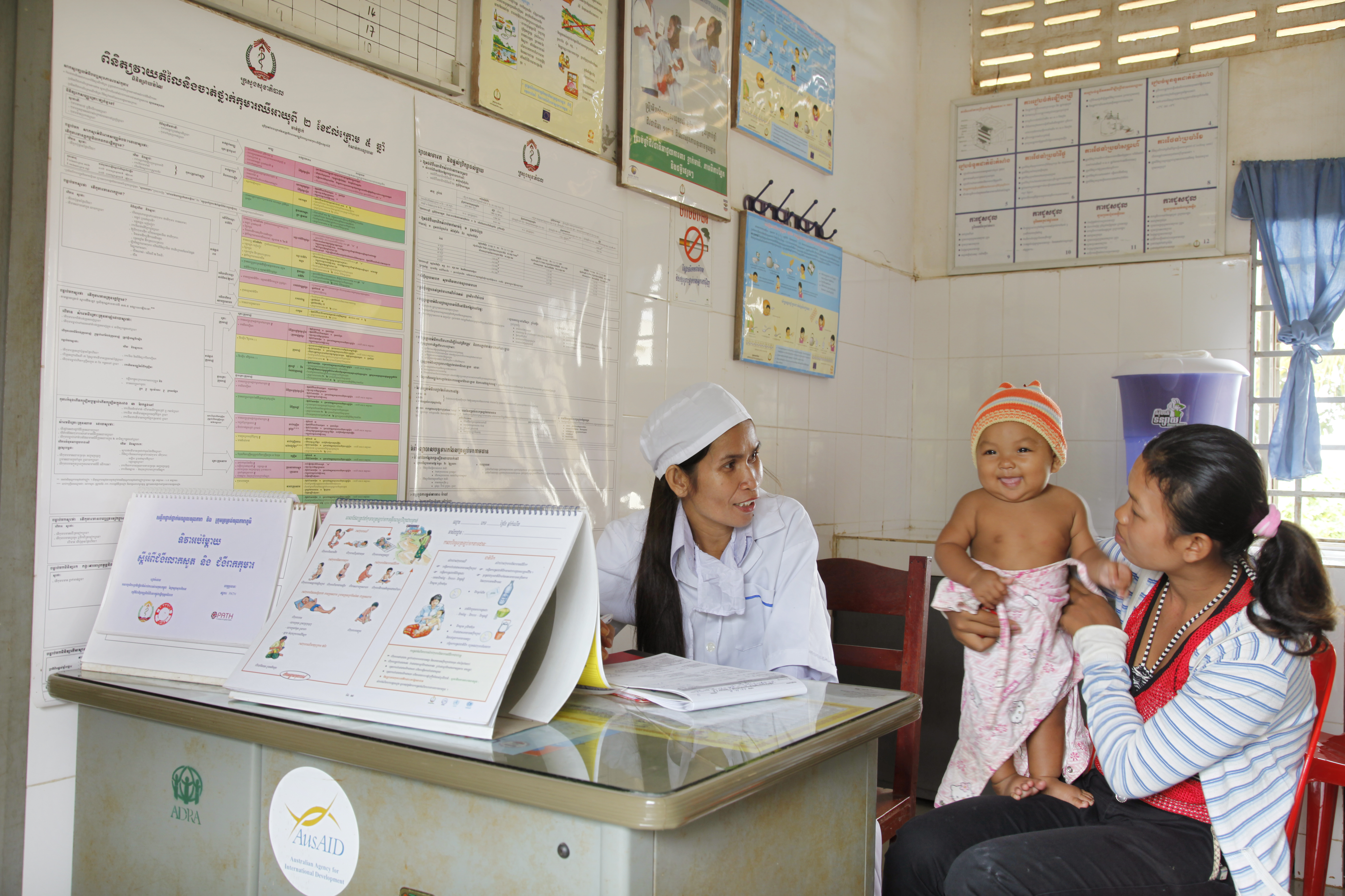 Mother holds smiling child at an ORS clinic in Cambodia.