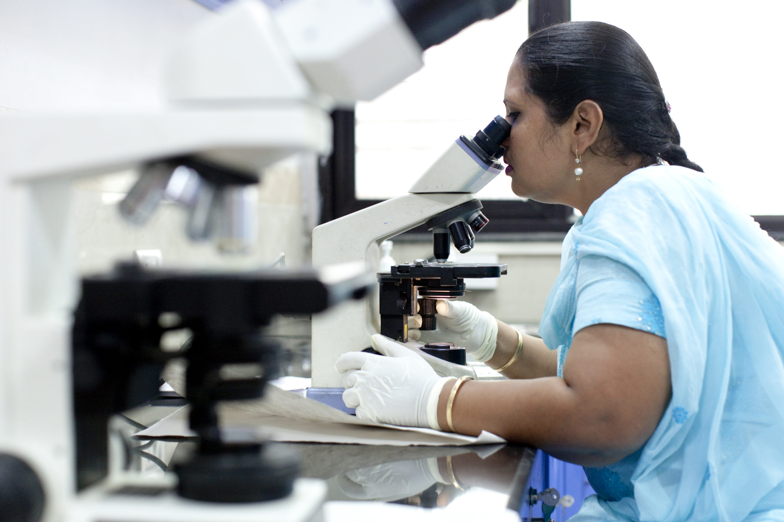 Indian woman looking into a microscope