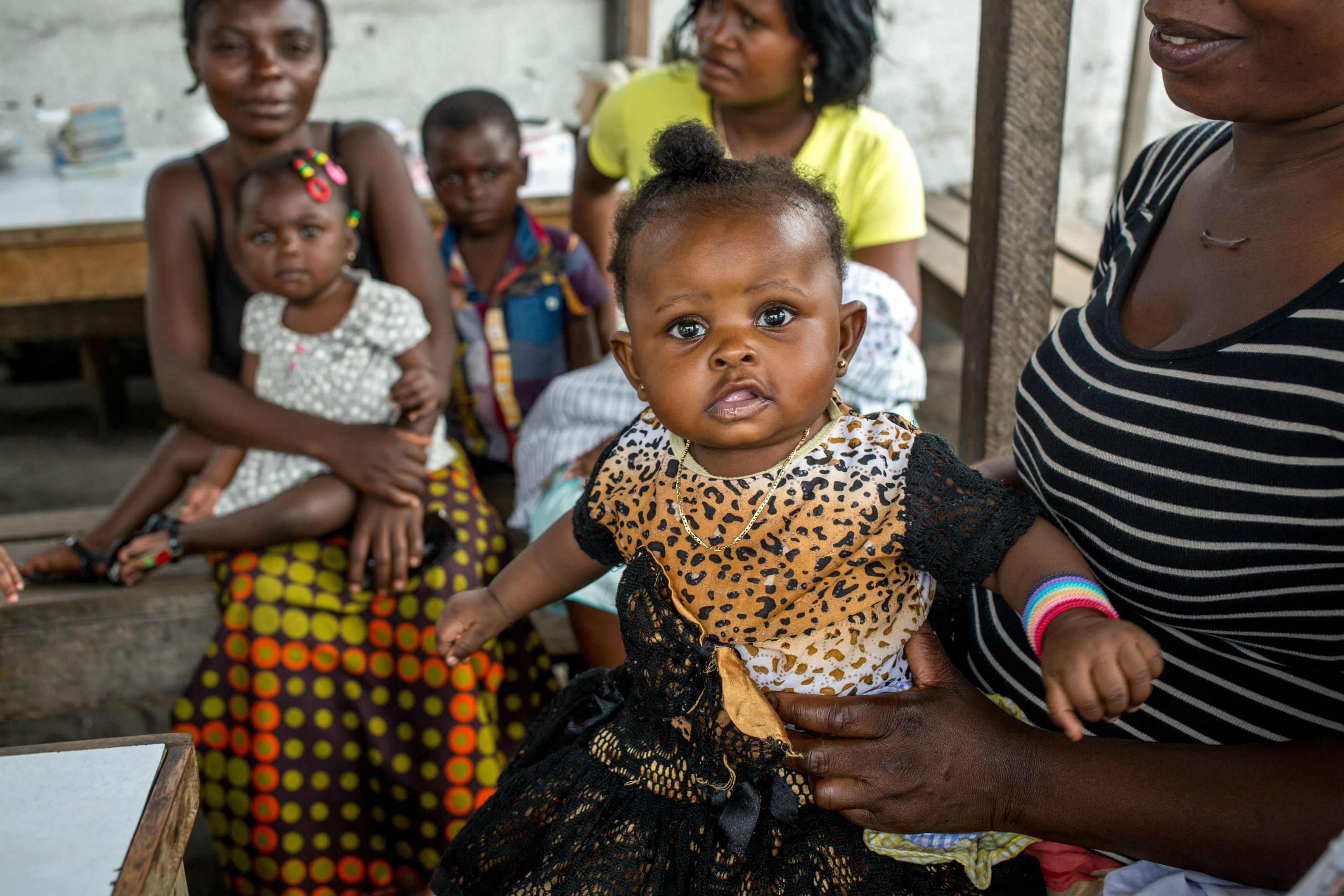 Young girl sits on her mother's lap. Photo: PATH/Goodwin