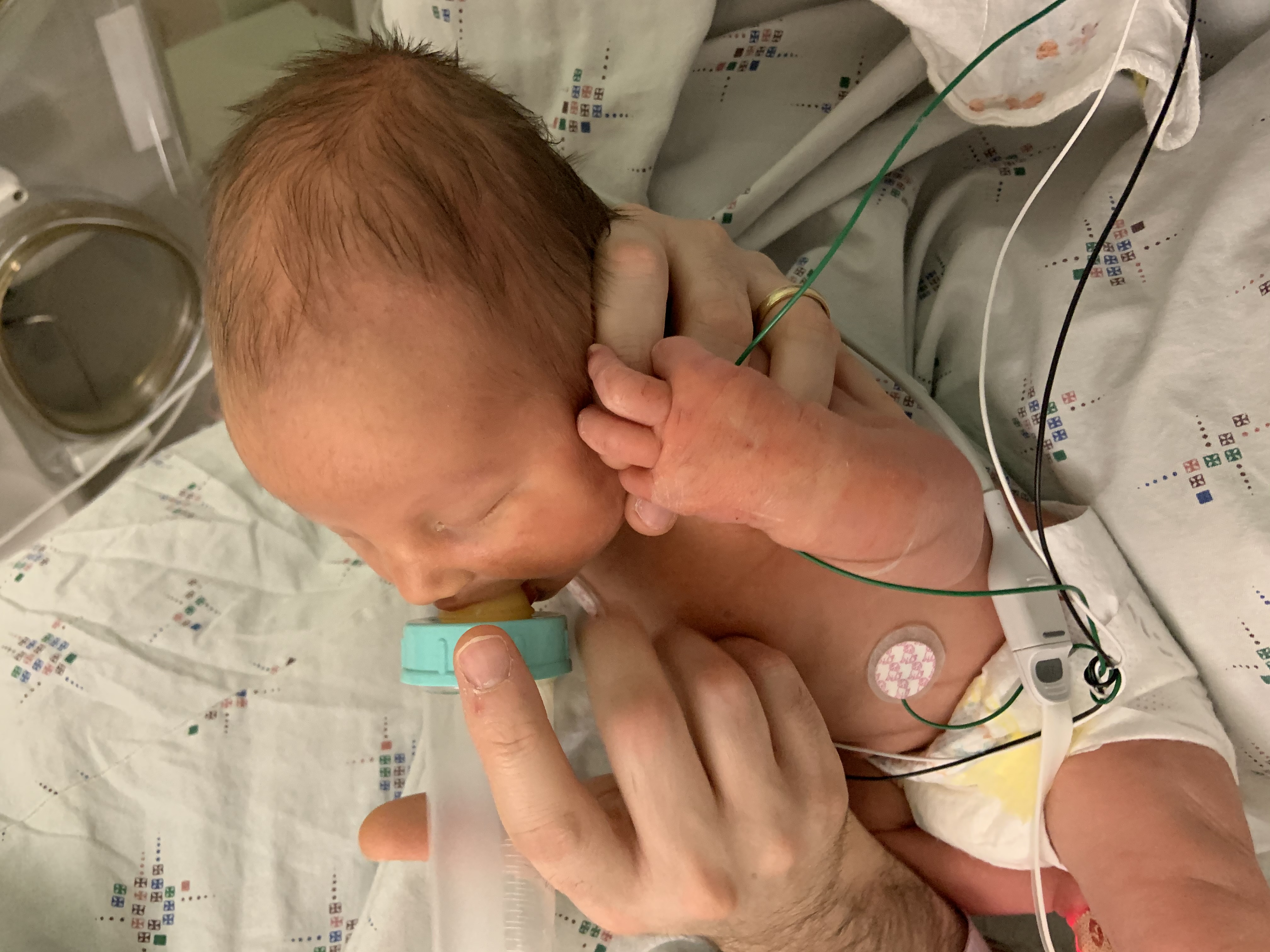 Author's son drinks donor breast milk out of a bottle in the NICU