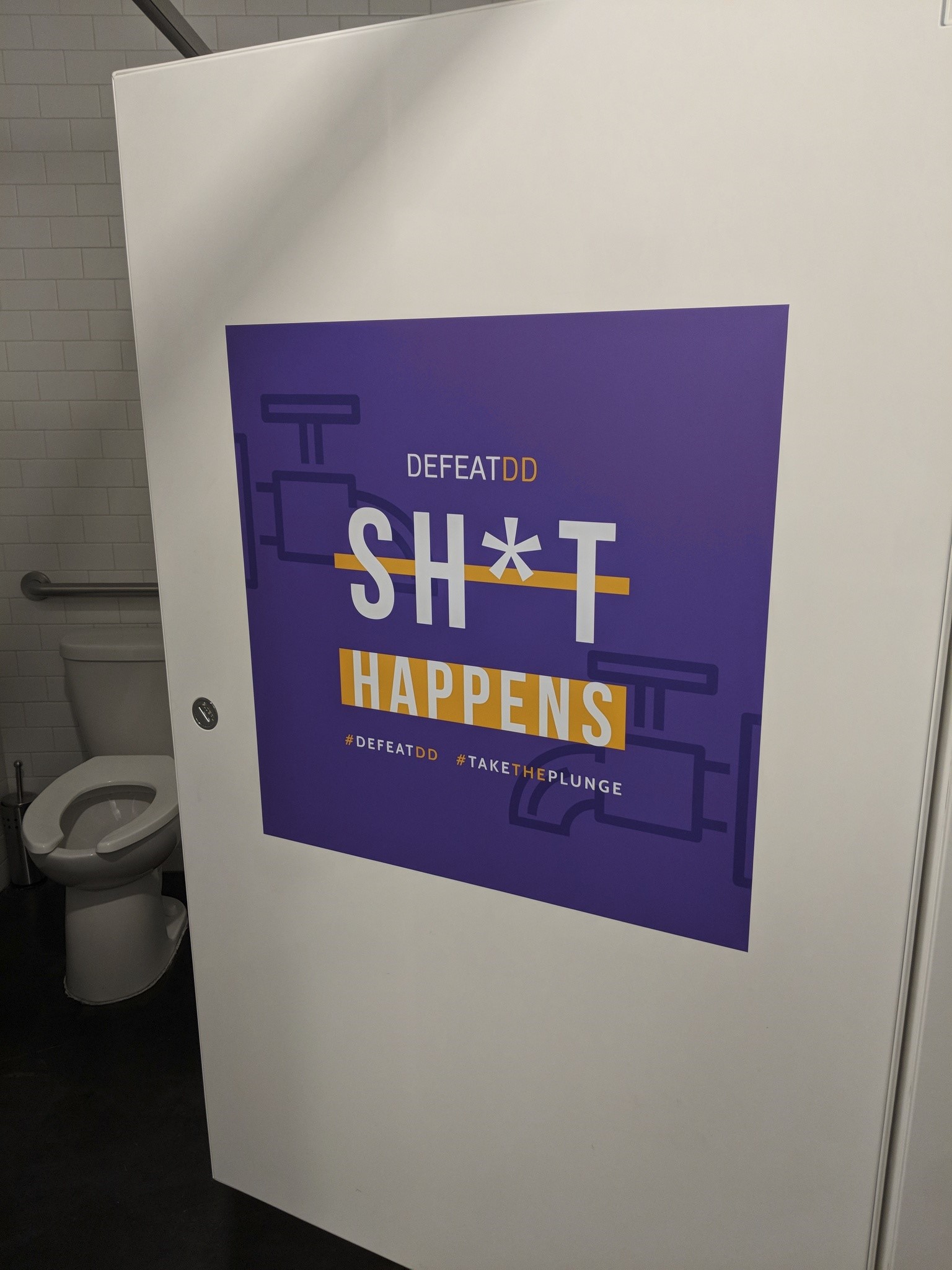 "Sh*t Happens" poster on bathroom door