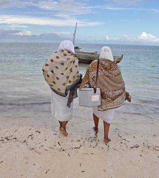 Two health workers with vaccines walking toward a boat