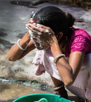 Indian woman splashes soapy water on her face