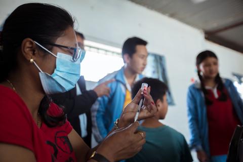 Health worker with mask holds a vaccine syringe
