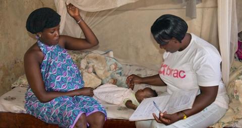 A CHW cares for a sick child next to her mother. BRAC Uganda