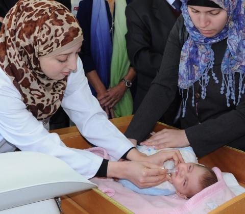 Infant in Gaza receives ROTAVAC from healthcare worker while mother looks on