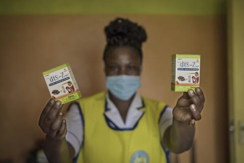 Nurse holds up a container in each hand which is co-packaged oral rehydration solution and zinc